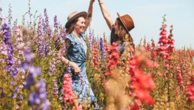 two women holding hands at the flower field
